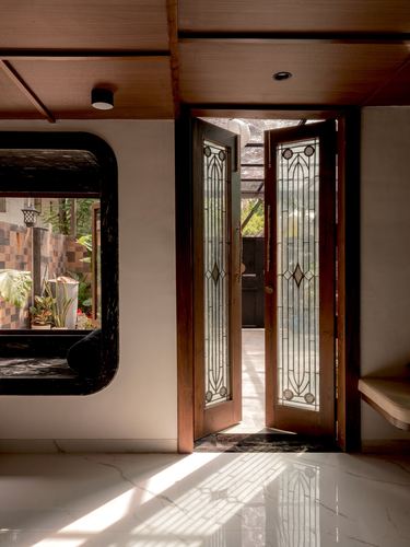 Foyer with open stained-glass wooden doors and a curved dark window frame onto a courtyard
