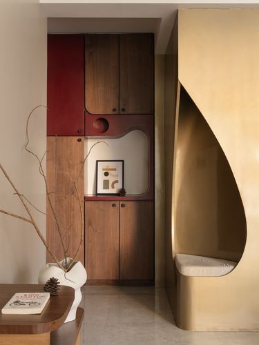 Foyer with gold curved niche seat beside a wood and red-lacquer cabinet on marble flooring