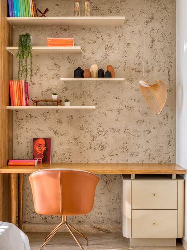 Study nook with floating shelves, textured plaster wall, wooden desk and leather chair