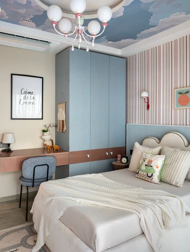Child's bedroom with cloud-painted ceiling, blue upholstered wardrobe, striped wall, and floral chandelier