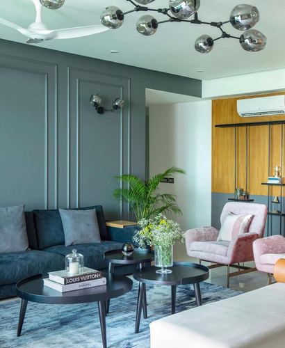 Living room with navy sofa, blush armchairs, nested black coffee tables and sputnik chandelier