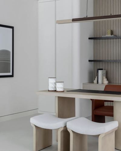 Minimalist dining nook with curved stools, wood table, fluted shelving and framed photograph