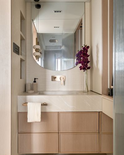 Bathroom vanity with arched mirror, wooden drawers, marble-look countertop and purple orchid