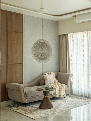 Beige chaise lounge sofa beneath a round carved wall medallion in a softly lit living room corner