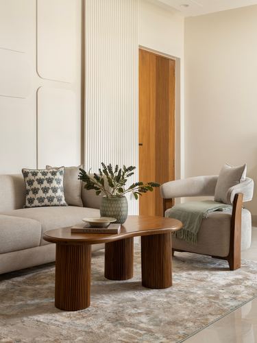 Neutral living room with fluted wall panel, teak coffee table, sofa and armchair