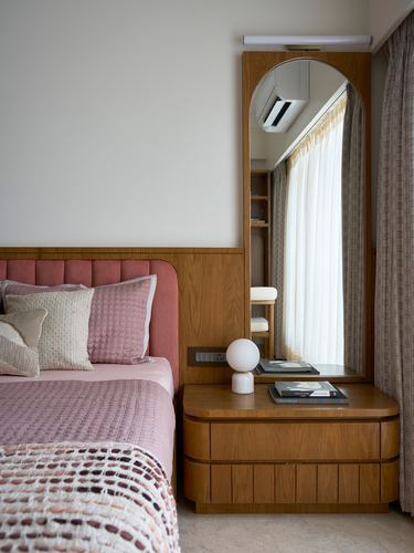 Bedroom corner with pink channel-tufted headboard and arched wood mirror nightstand