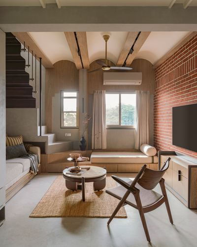 Living room with exposed brick wall, arched wooden ceiling beams, window seat and round coffee table