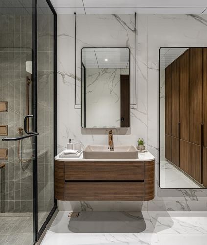 Bathroom vanity with wood cabinetry, vessel sink, suspended mirror, and marble-look tiled walls