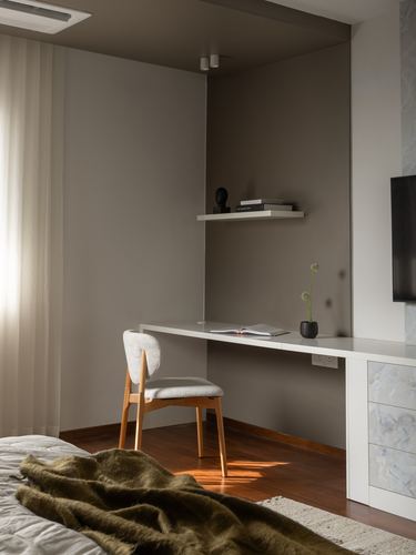 Corner study nook in bedroom with floating shelf, desk, and wooden chair, warm afternoon light