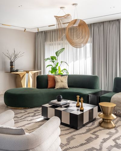 Living room with curved green velvet sofa, checkerboard coffee table, and sculptural woven pendant lights