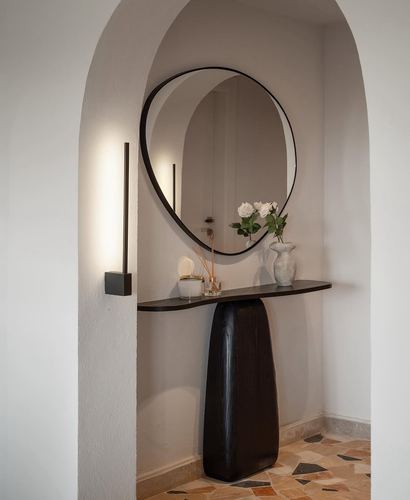 Arched niche foyer with round mirror, dark wood console, roses, and terrazzo floor