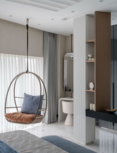Bedroom corner with rattan hanging chair beside a fluted-panel dressing nook and shelving niche
