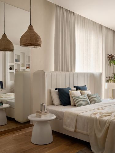 Cream bedroom with channel-tufted headboard, rattan pendant lights, and round side table on wood floor