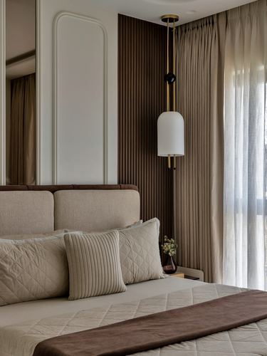 Bedroom corner with fluted wood wall, brass pendant light, and quilted upholstered bed