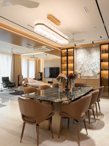 Open-plan dining and living space with marble table, leather chairs, and lit display shelving