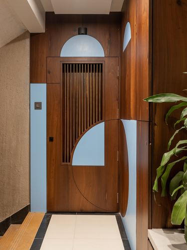 Wooden entrance door with vertical slats and blue geometric arc motifs in a foyer