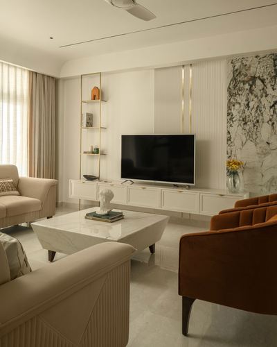 Living room with cream sofas, rust velvet armchair, marble coffee table, and fluted TV wall panel