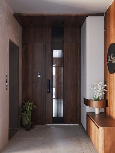 Wooden entry door with vertical glass slats beside a floating wood console in a foyer