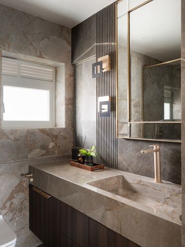 Marble-clad bathroom vanity with vessel sink, brass faucet, fluted panel and gold-framed mirror