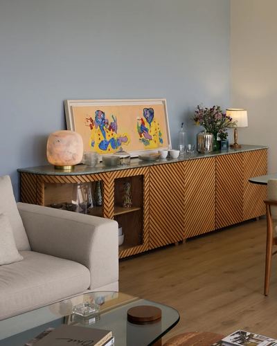 Living room with chevron wood sideboard, stone top, artwork, and beige sofa against blue wall