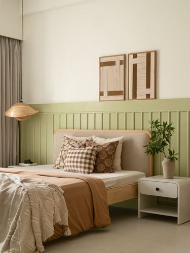 Bedroom with sage wainscoting, wood-framed upholstered bed, woven wall art and rattan pendant light