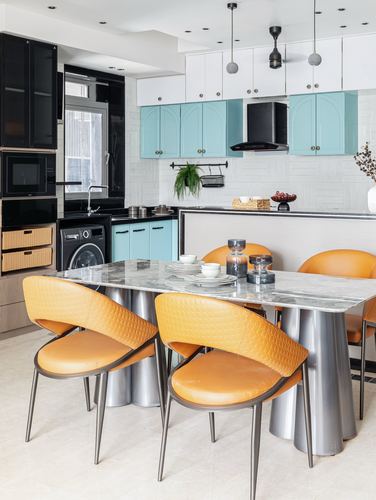 Kitchen-dining space with mustard leather chairs, marble-top table, and teal arched cabinets