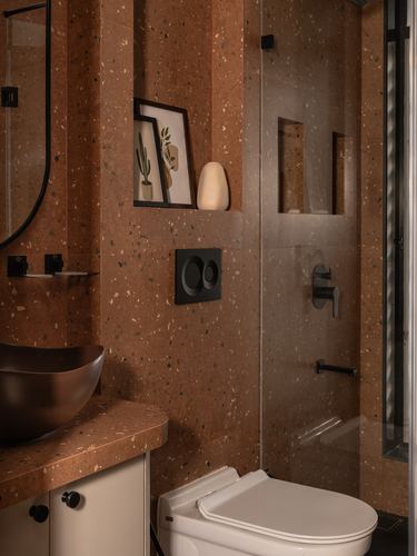 Terrazzo bathroom with bowl sink, framed prints, and glass shower enclosure