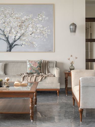 Beige living room with wooden sofas, glass coffee table, and a framed blossom painting above