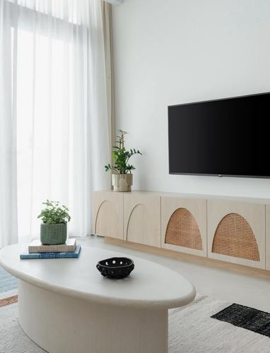 Minimalist living room with cane-arched wood console, sculptural oval coffee table and sheer curtains