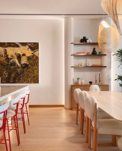 Dining and kitchen area with red stools, boucle chairs, and sculptural woven pendant lights