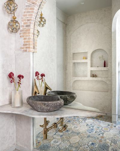Bathroom vanity with carved stone sink, arched brick niche, and patterned tile floor