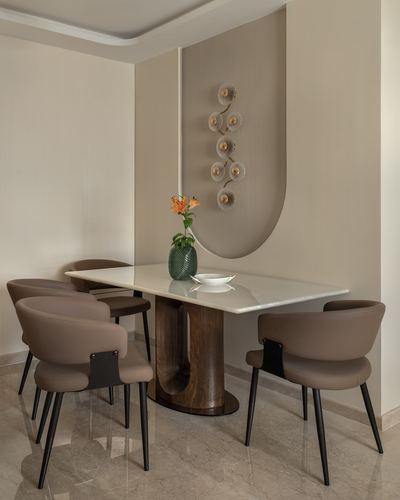Dining table with marble top and curved wood base beneath an arched fluted wall niche with floral sconce
