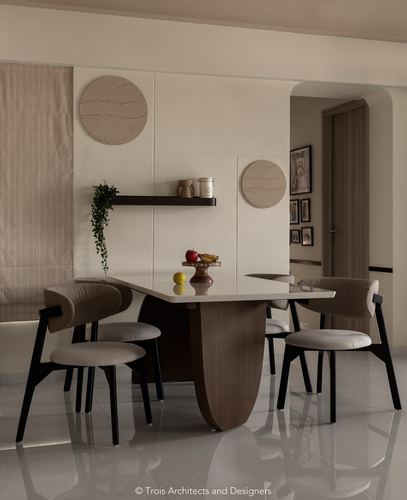 Dining area with sculptural wood table, cane-back chairs, and round stone wall discs above a floating shelf