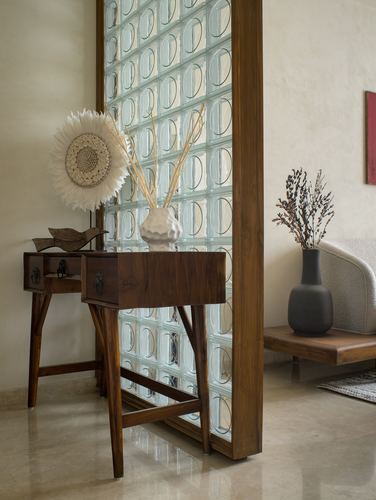 Entryway with wooden console table beside a glass block partition and ceramic vases