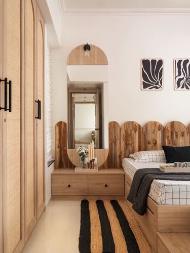 Bedroom with arched wooden headboard, cane wardrobes, arched mirror and striped rug