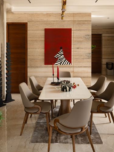 Dining room with marble table, taupe chairs, and a red zebra-patterned artwork on a stone wall
