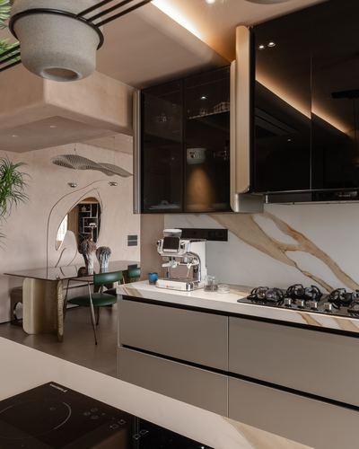 Modern kitchen with veined stone backsplash, dark glossy cabinets, and dining area visible beyond