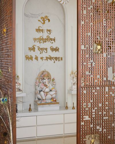 Marble pooja niche with Ganesha idol framed by a carved wooden jali screen