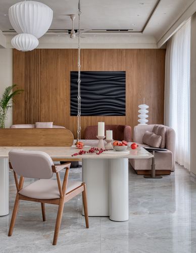 Dining area with pill-shaped marble table, blush sofa, and wave-textured art on wood panelling