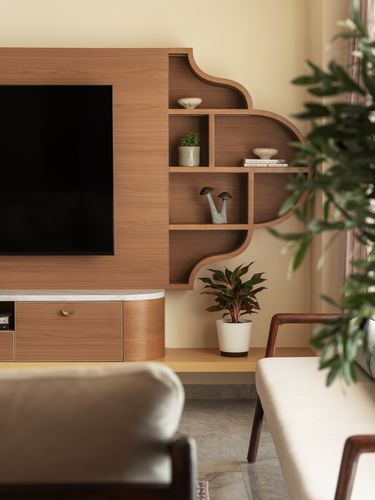 Wood-panelled tv unit with scalloped shelf niches, stone console, and armchairs in warm-toned living room