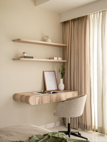 Floating wood desk with shelves beside curtained window, upholstered chair, bedroom corner