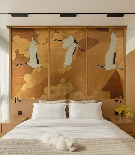 Bedroom with white bed below a three-panel gold crane wallpaper headboard wall