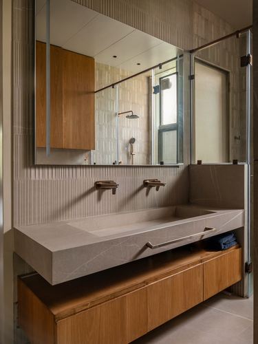 Bathroom with floating carved stone sink, wooden vanity, fluted tile wall and large mirror