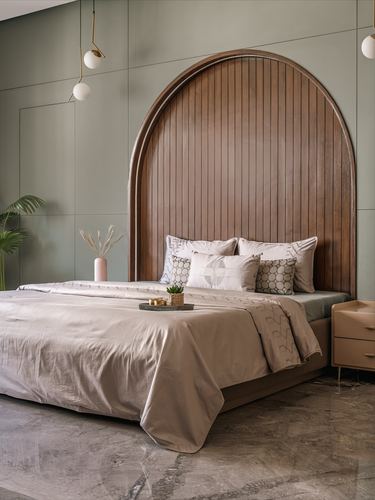 Bedroom with arched fluted wood headboard against sage green paneled wall, beige linens