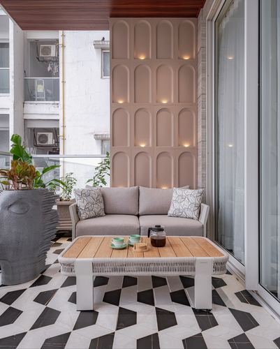 Balcony seating with grey sofa, wood coffee table, and glowing arched niche wall on graphic tiled floor