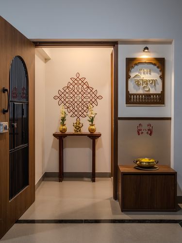 Entryway foyer with a decorative wall motif above a wooden console with a brass Ganesha idol