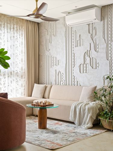 Neutral living room with textured wall relief, beige sofa, glass-top coffee table on wood base, and terracotta armchair