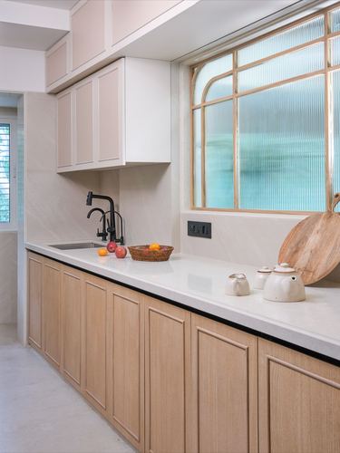 Minimalist kitchen with wood cabinetry, white countertop, and arched ribbed glass window