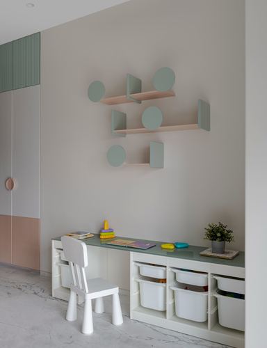 Child's study nook with sage desk, storage bins, and geometric wall shelving