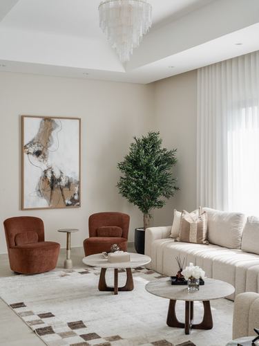 Neutral living room with rust swivel chairs, marble coffee tables, and beige sofa
